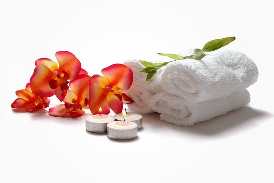 Red yellow orchids, tea light candles and white towels rolled up